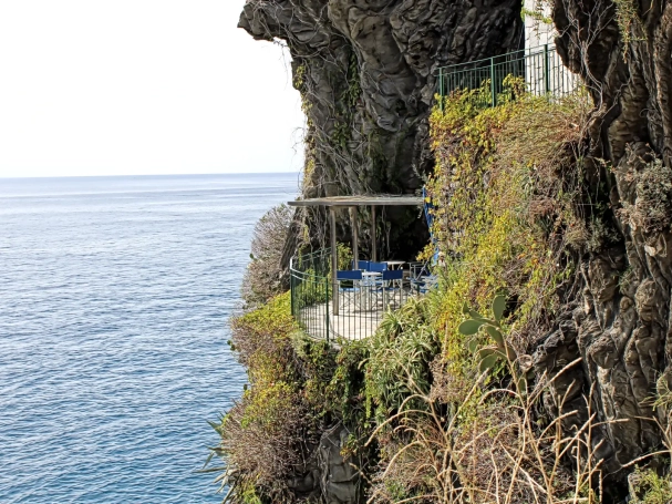 Private blue terrace seating on a steep cliffside balcony overlooking the Ligurian Sea in Cinque Terre, Italy.