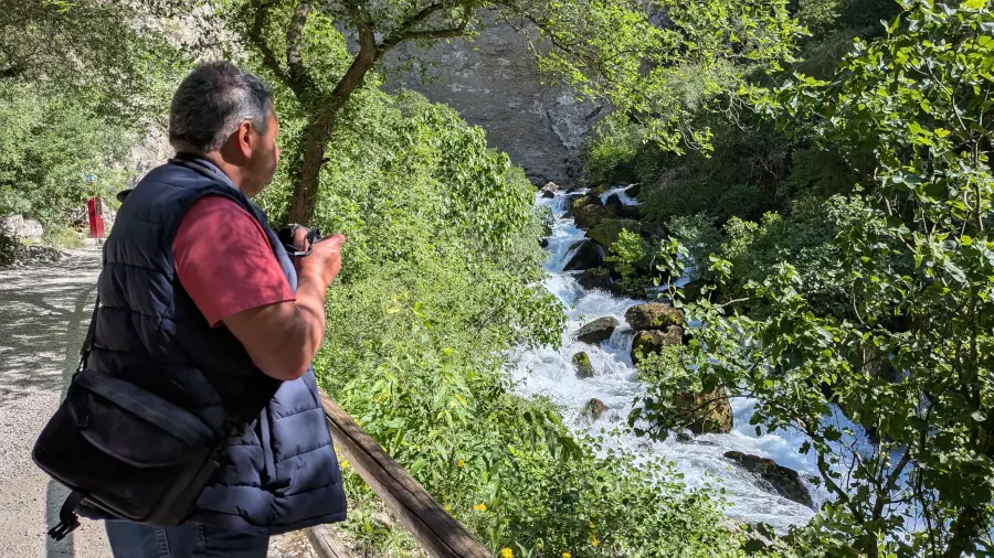 Landscape photographer observing a waterfall in a lush green canyon