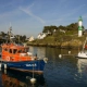 Rescue boat SNS 206 moored in a scenic harbor with a lighthouse and coastal houses in the background