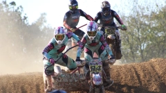 Front view of two sidecarcross teams racing head-to-head on a dusty dirt track