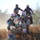 Front view of two sidecarcross teams racing head-to-head on a dusty dirt track